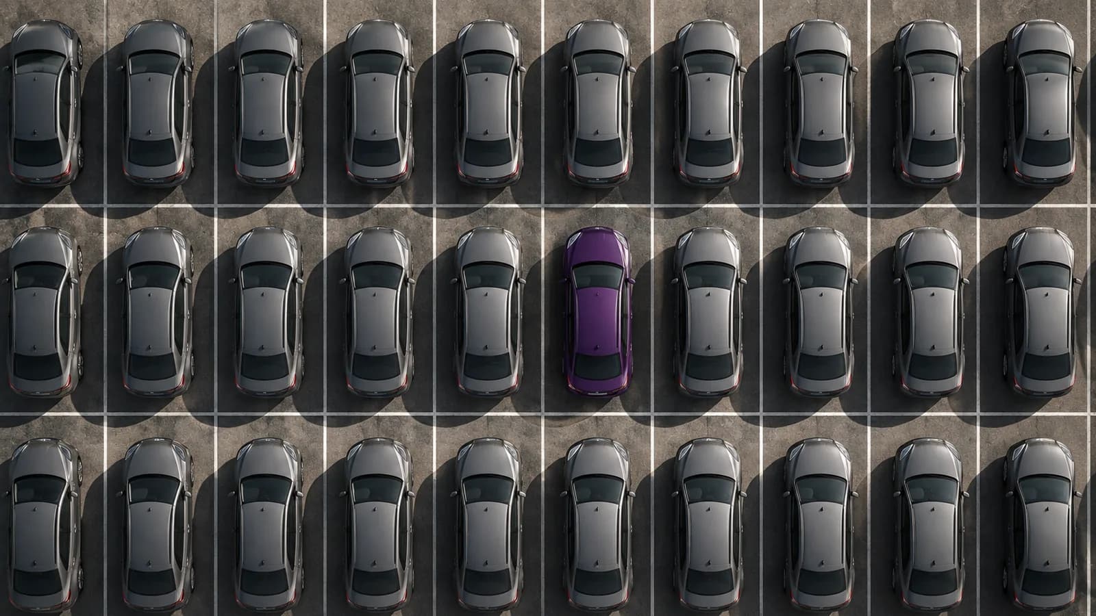 A car park of identical grey cars with one violet car among them.